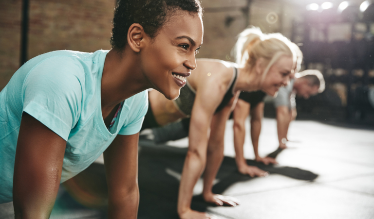 Smiling young woman doing pushups in a gym exercise class