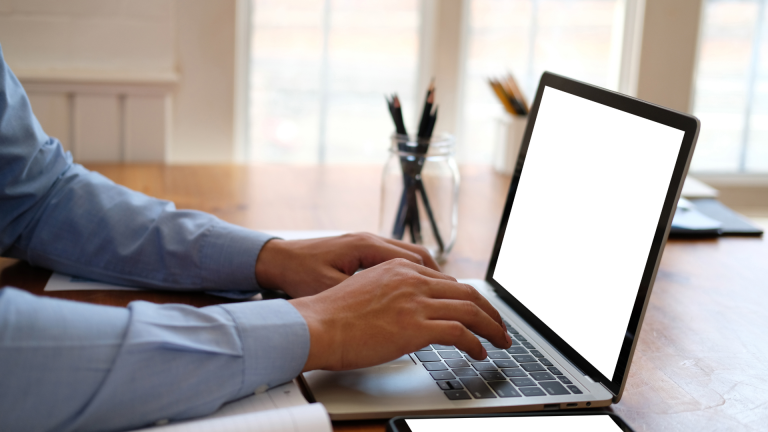 a person typing on a laptop computer with a blank screen