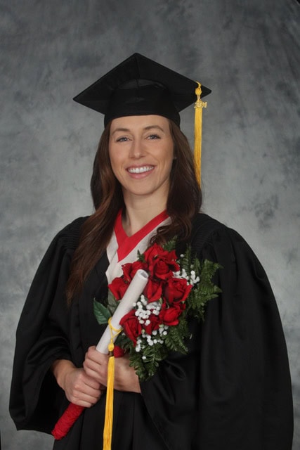 A smiling woman in a graduation outfit