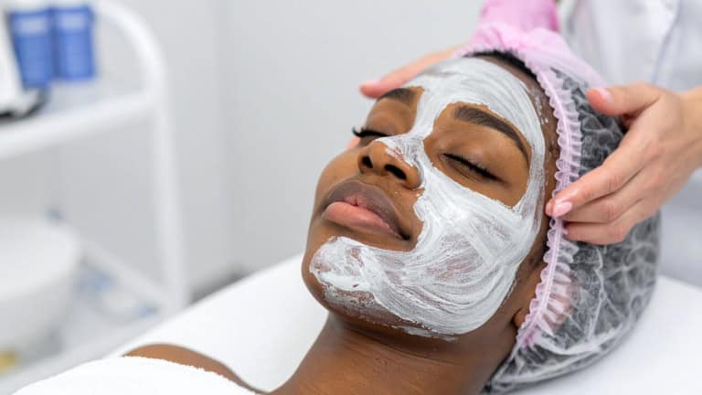 A woman lies back relaxing while receiving a facial treatment with a white mask.