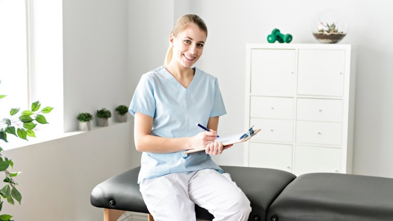 A person is sitting on a chair and holding a clipboard.